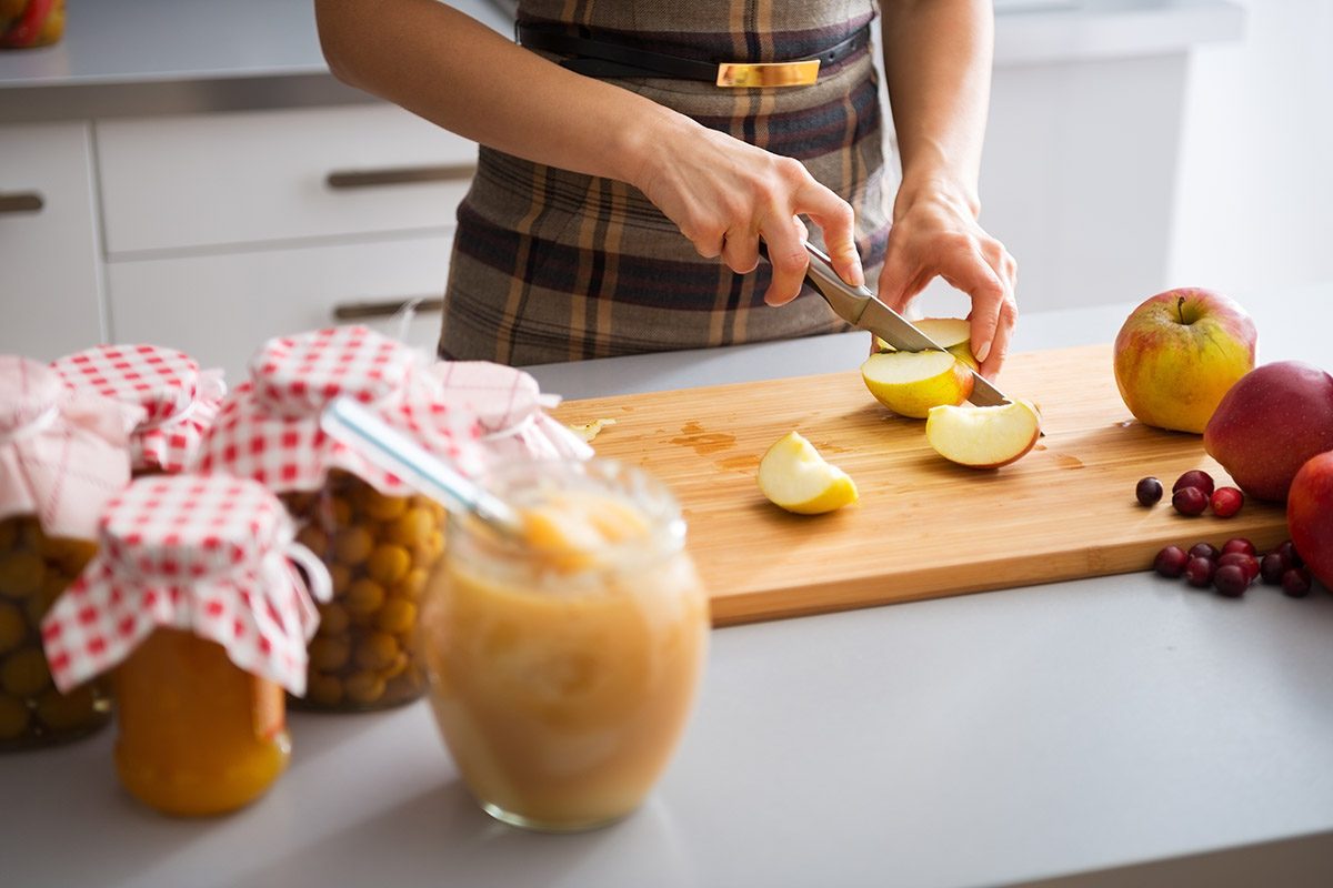 Closeup on young housewife cutting apple for jam;