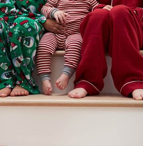 Three Children In Pajamas Sitting On Stairs At Christmas