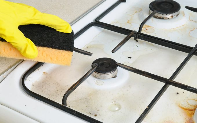 cleaning of dirty gas stove burners in kitchen room