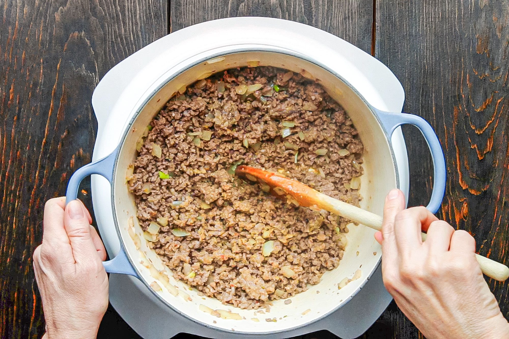 Cooking Beef in A Pan on Wooden Surface to make Lasagna