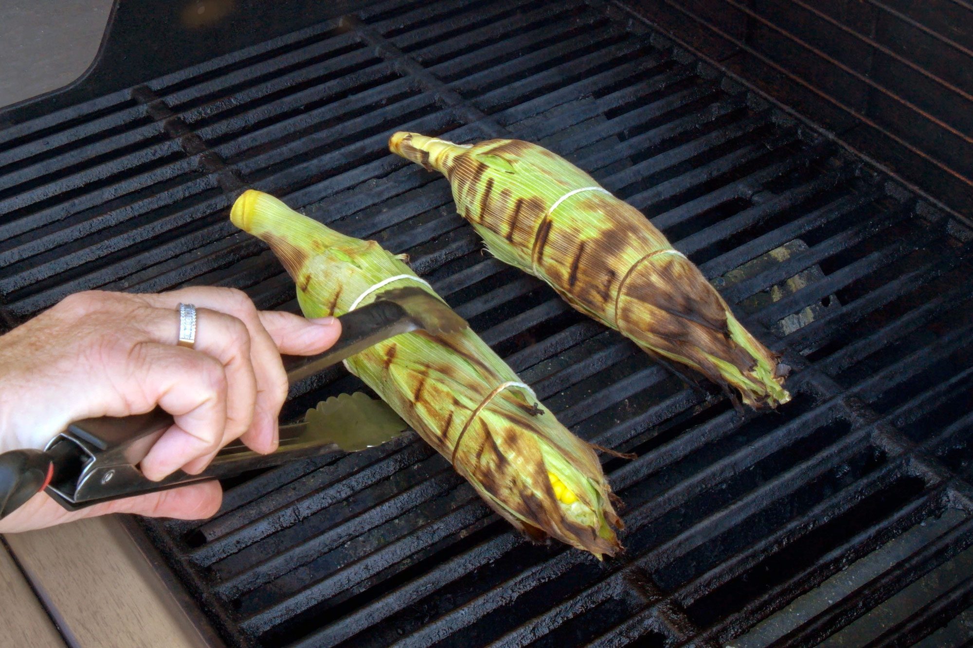 grilling corns over griller and turning corn using tong