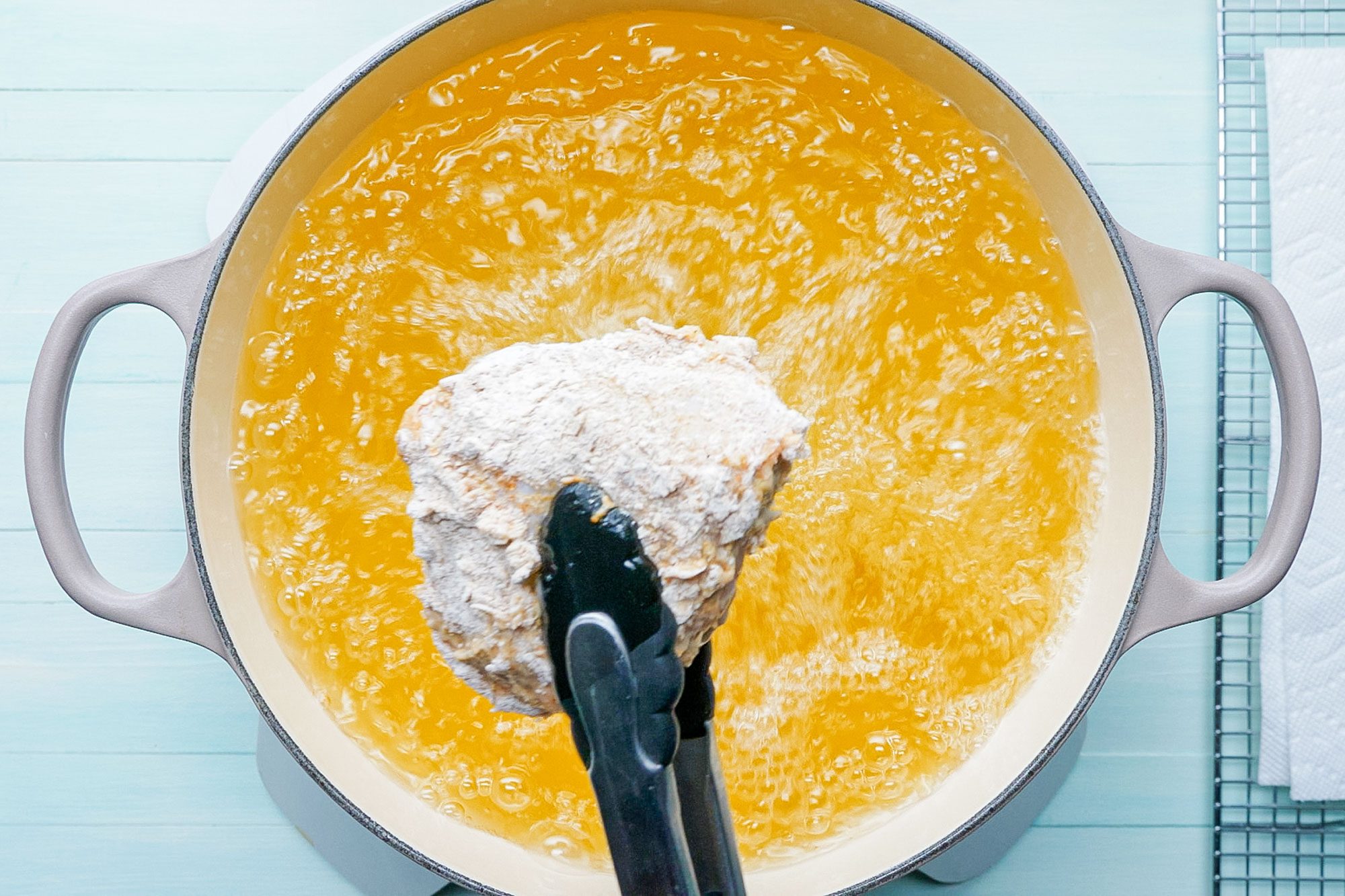 Chicken Ready to Fry Picked with Cooking Tong and Boiling Oil in a Pot