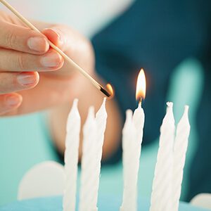 Woman lighting the candels on a birthday cake.