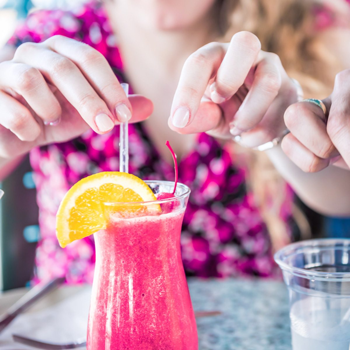 Closeup of two alcoholic summer drinks, strawberry daiquiri and pina colada, in restaurant with people