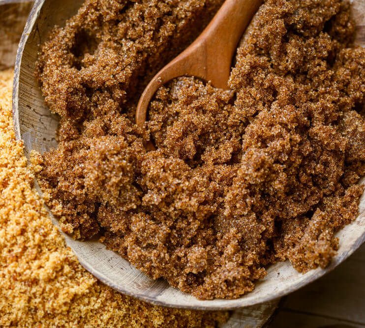 soft brown dark sugar and unrefined sugar cane in bowls