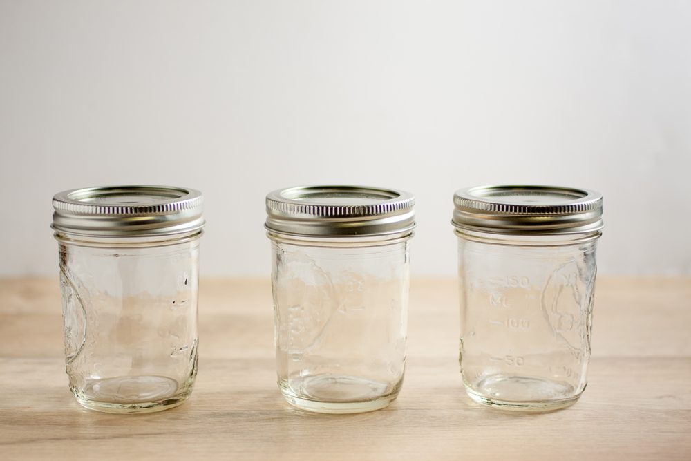 Empty canning jars await use on a wooden table