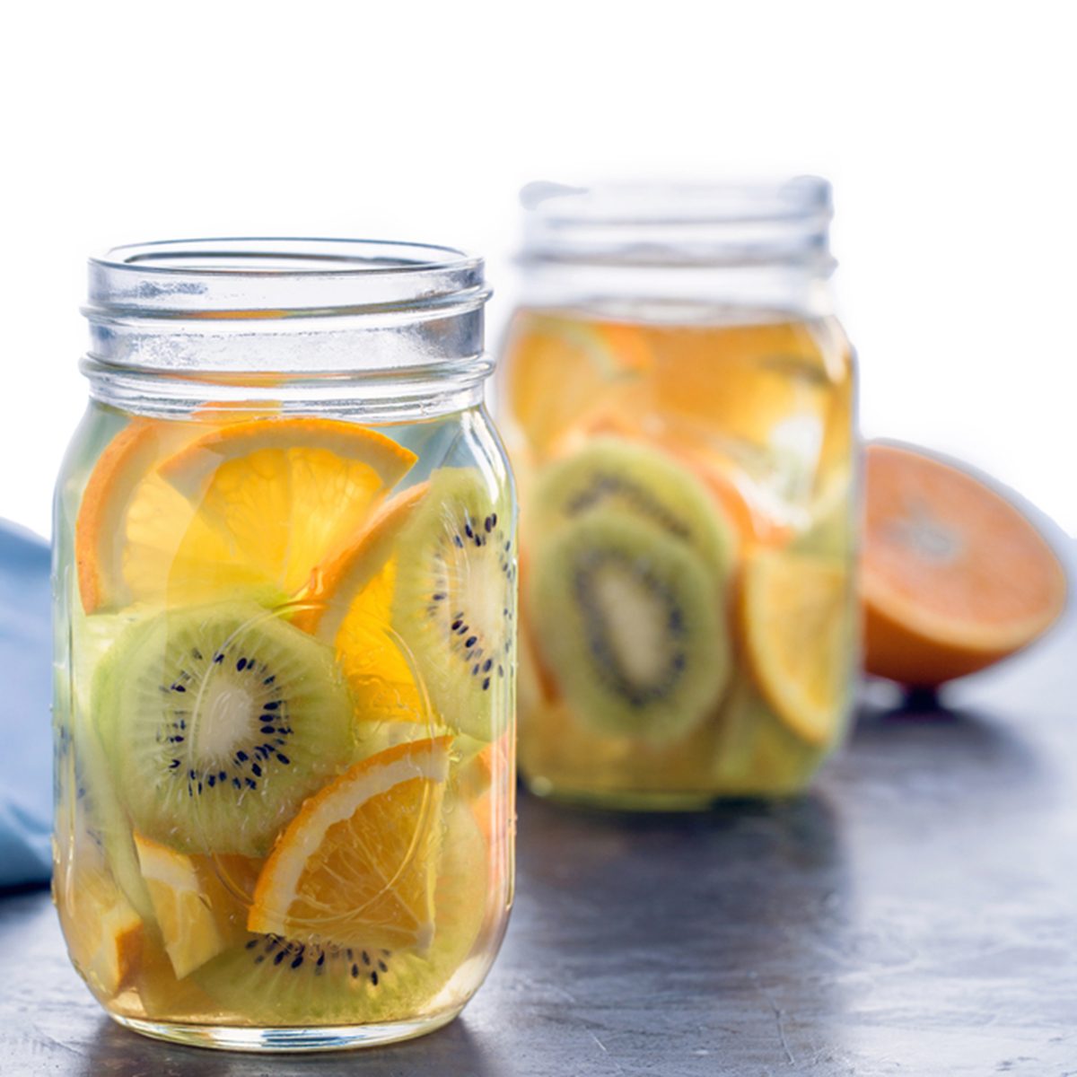 Infused water with kiwi and orange in jars, partly isolated