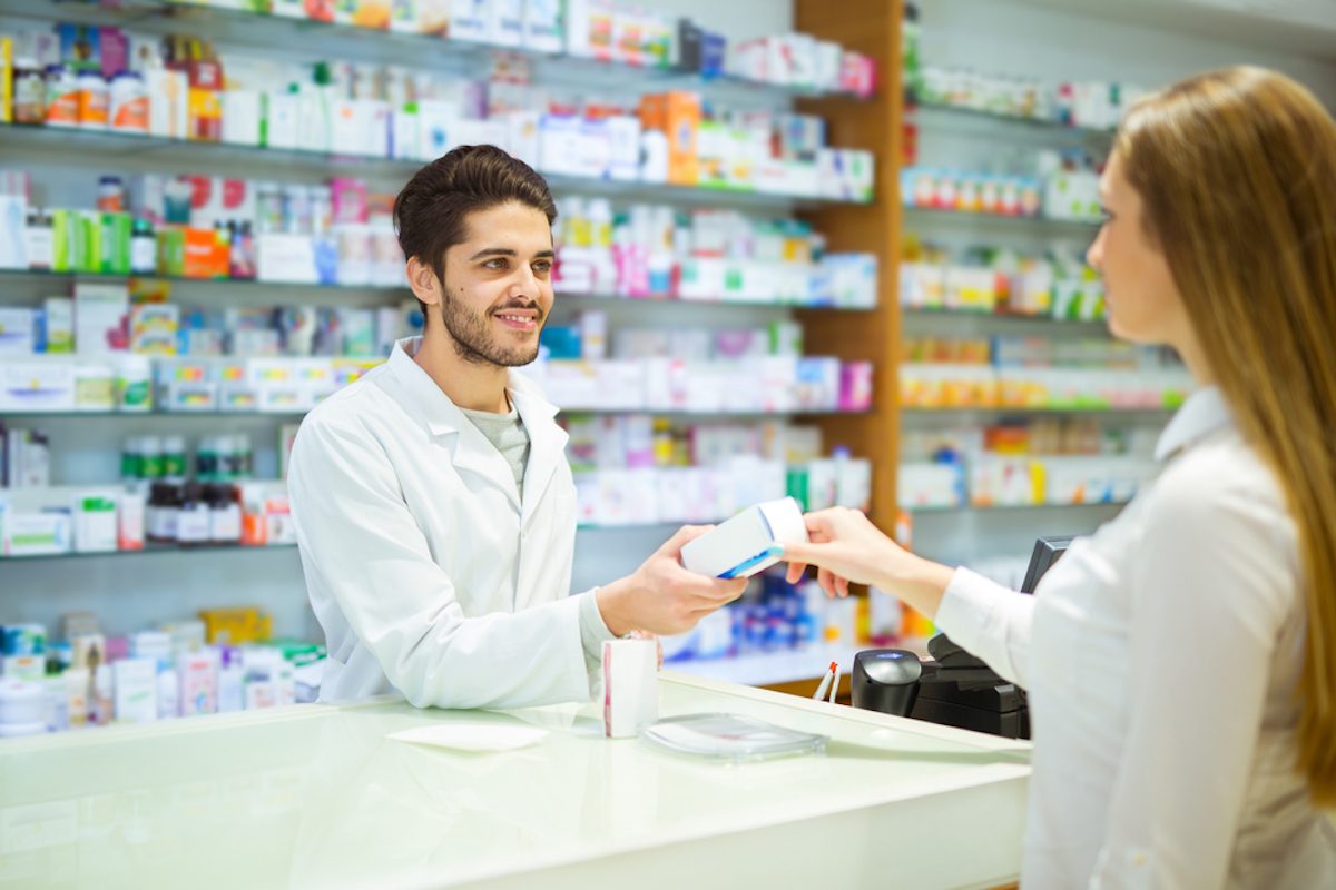 Experienced pharmacist counseling female customer in modern pharmacy