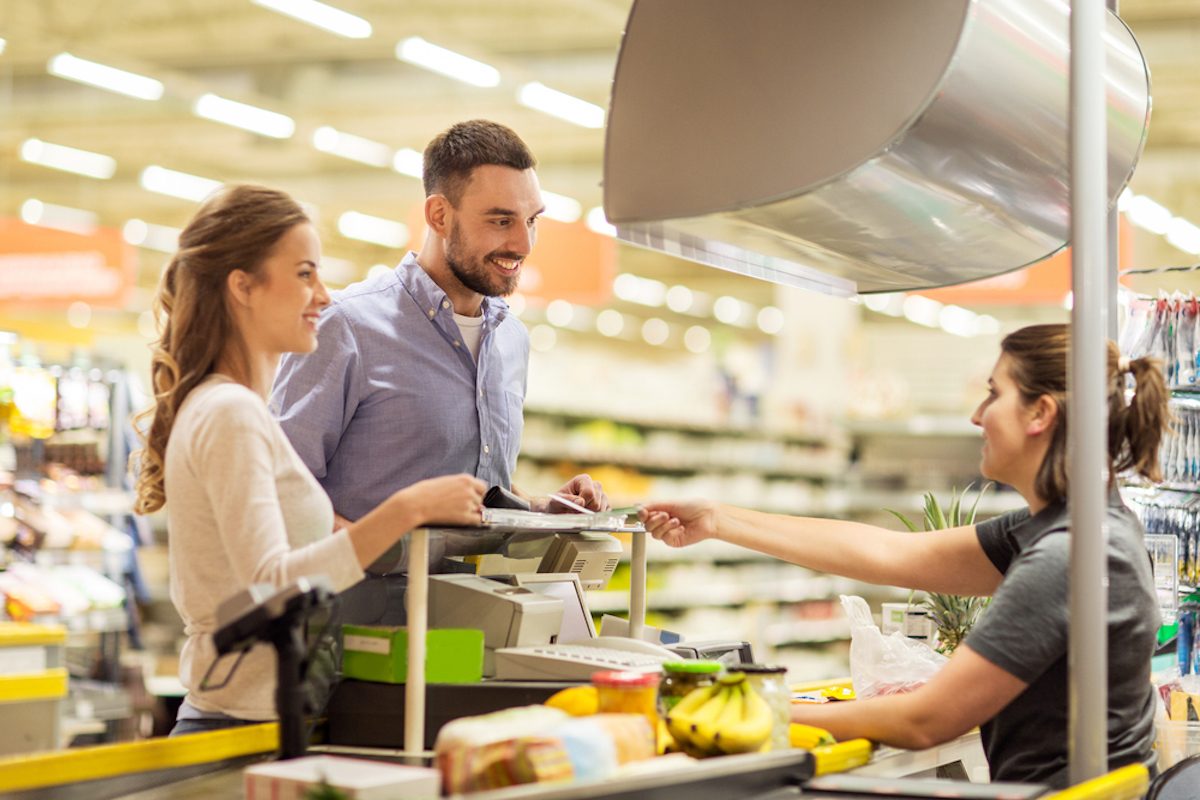 happy couple buying food at grocery store or supermarket cash register.