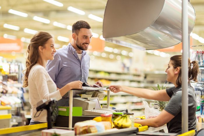 happy couple buying food at grocery store or supermarket cash register.
