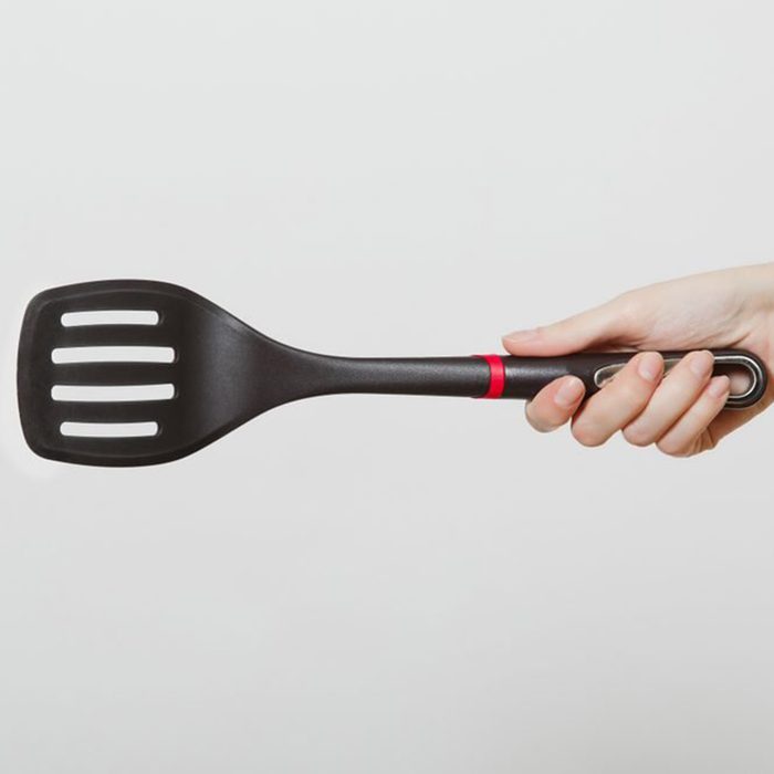 Close up of female hand horizontal holding black spatula isolated on white background.