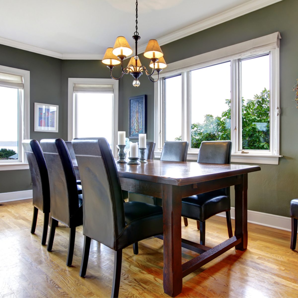 Large green dining room with leather chairs and large windows.