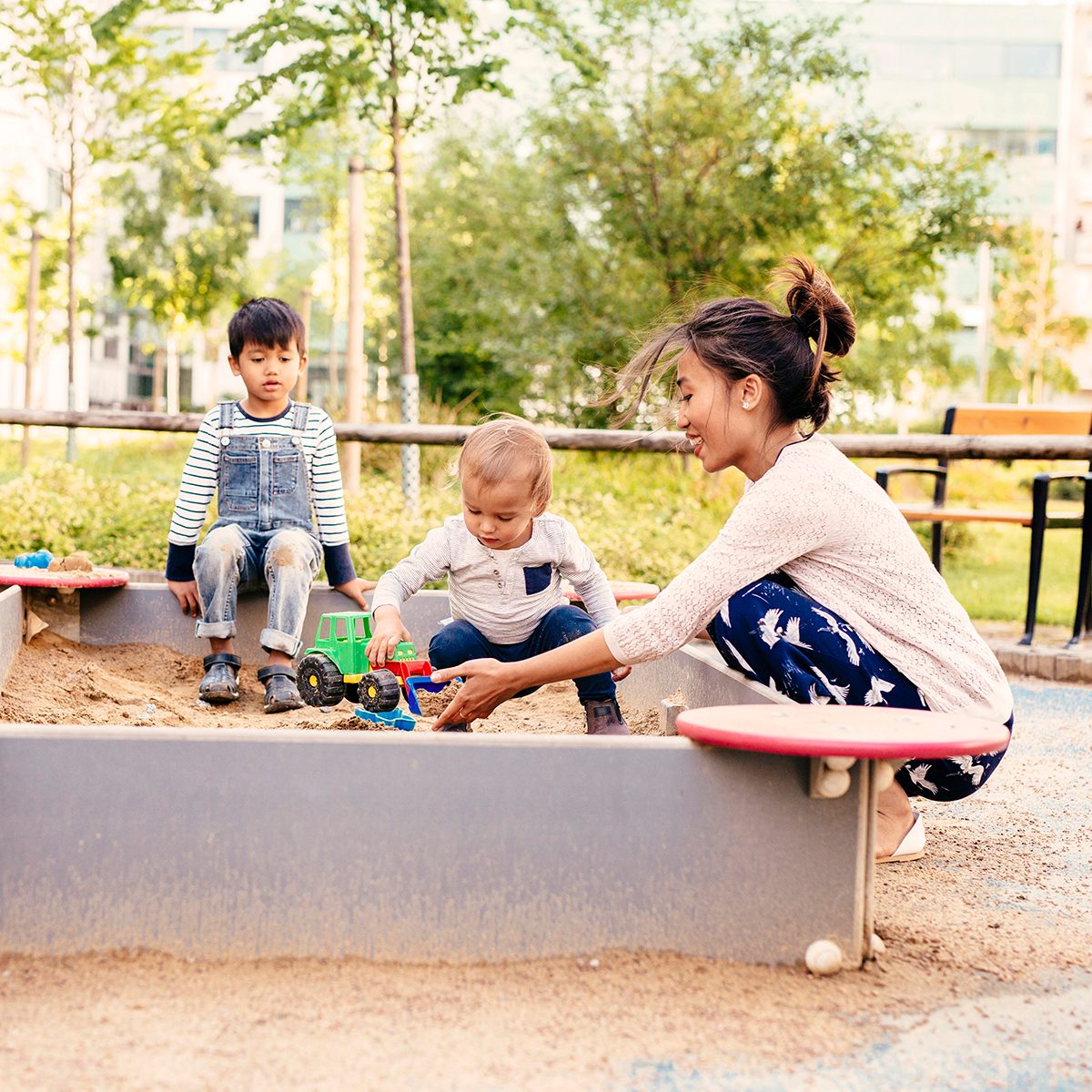 Mother playing with sons (2-3, 4-5) in sandbox