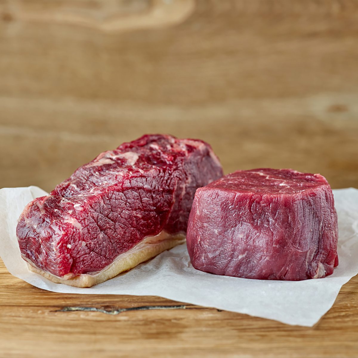 raw strip loin and fillet mignon steak on wooden table