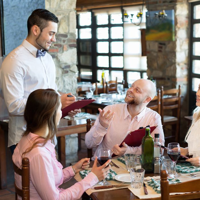 Relaxed adults people having dinner and respectful waiter