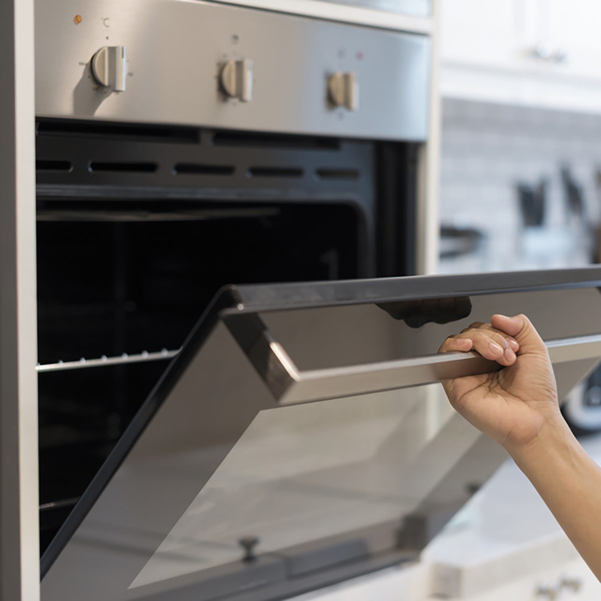 Hands open the oven in the kitchen