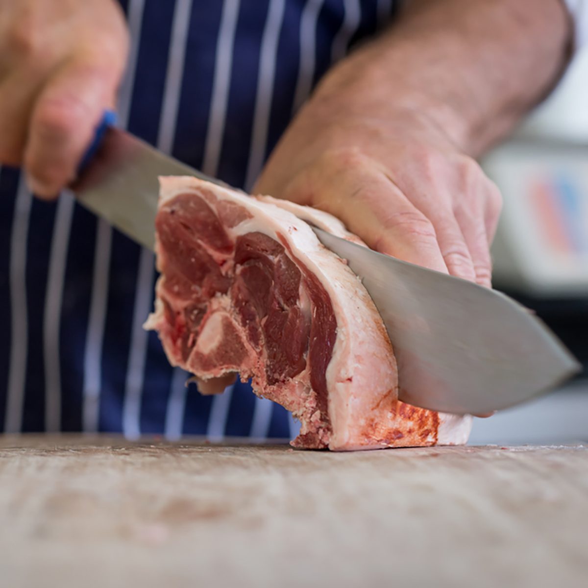 Friendly man preparing raw meat at the butchers