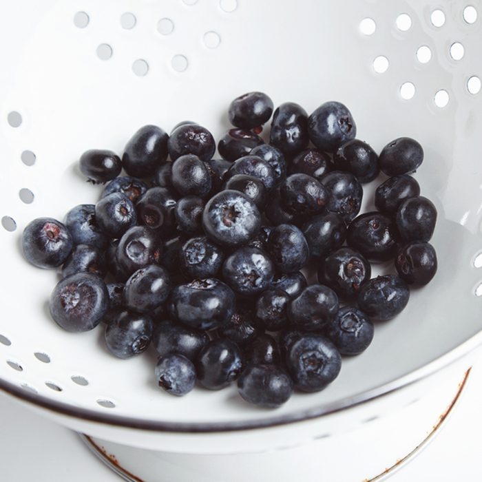 Heap of fresh blueberries in old enamel stainer