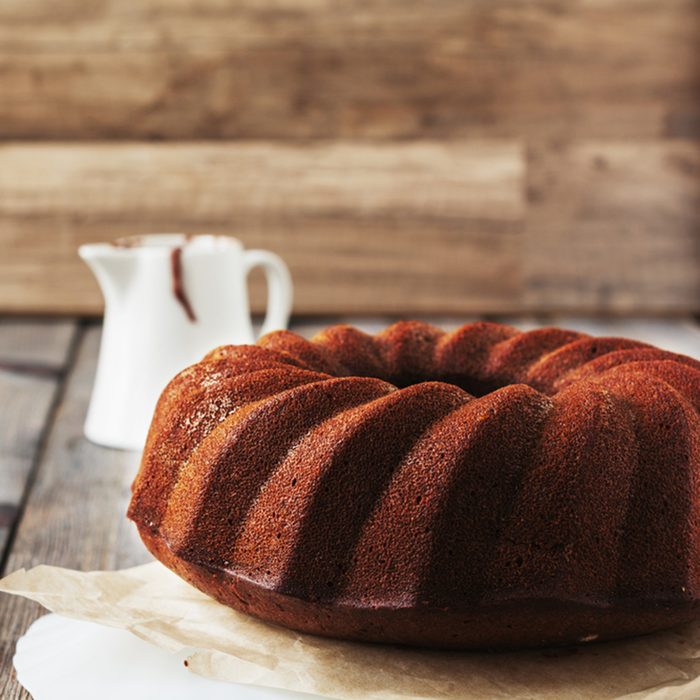 Chocolate Bundt cake with chocolate glaze on an old wooden table background.