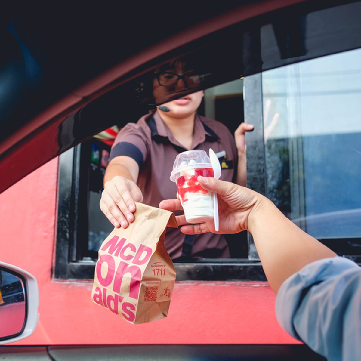 Unidentified customer receiving hamburger and ice cream after order and buy it from McDonald