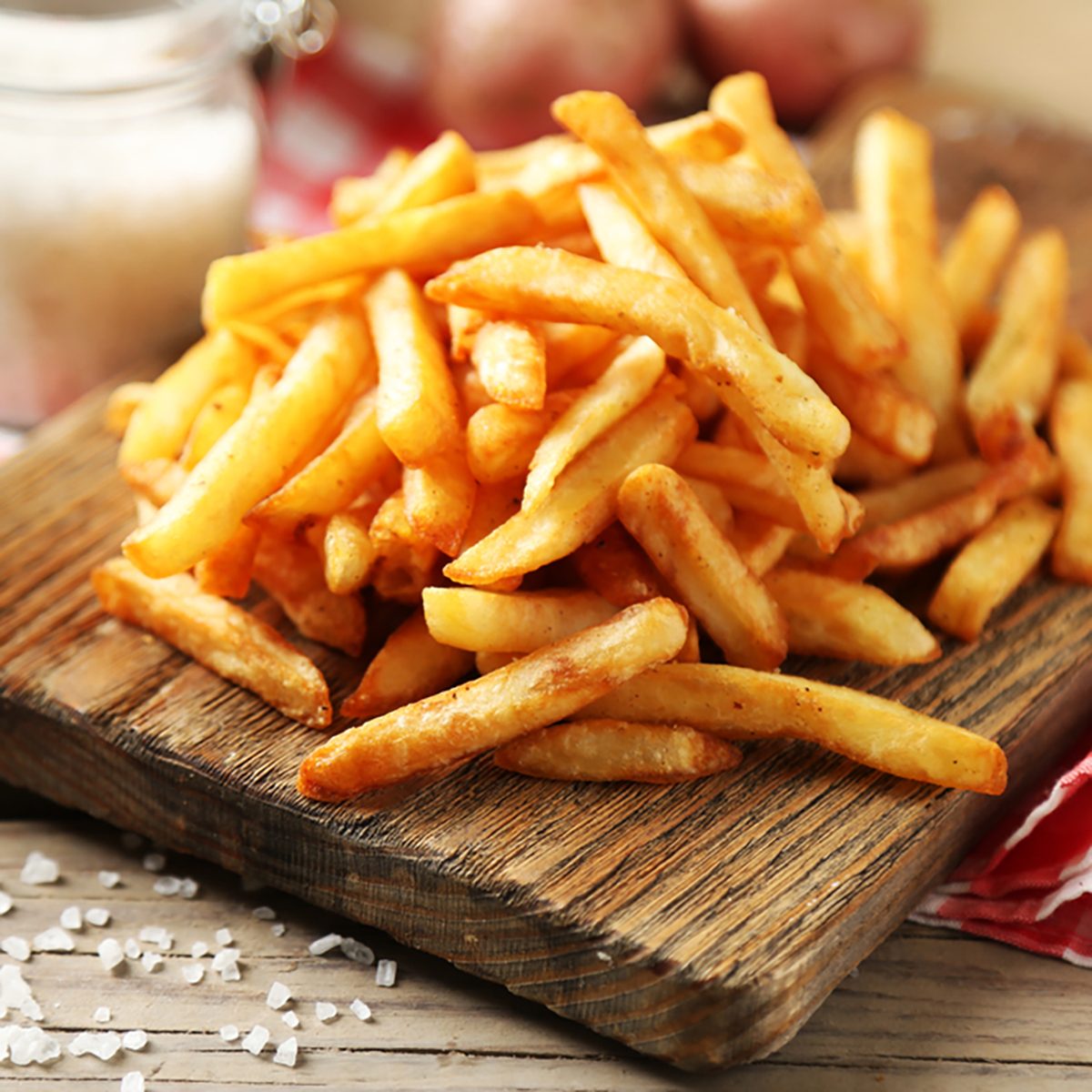 Tasty french fries on cutting board, on wooden table background