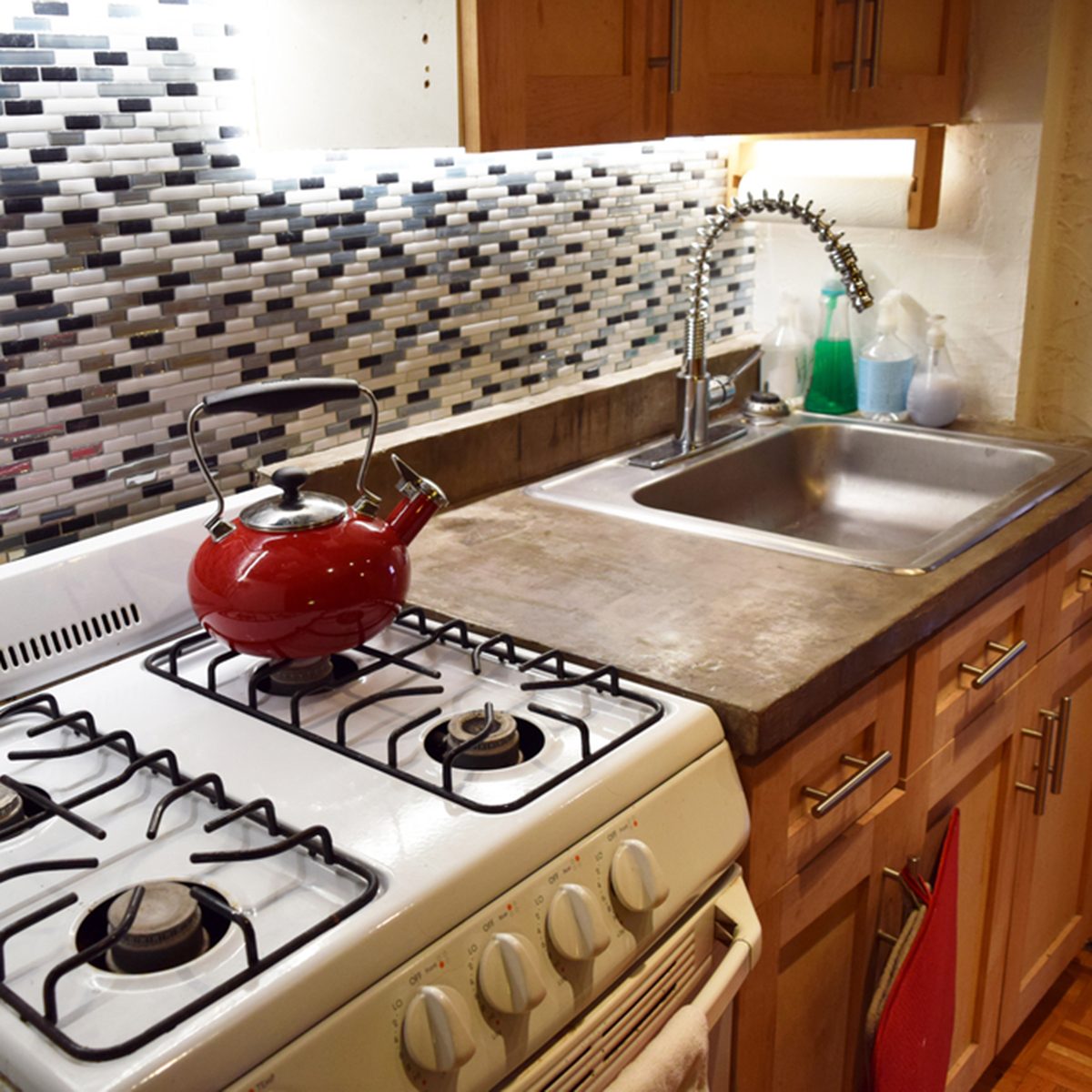 Clean kitchen with kettle on stovetop and concrete countertops in an apartment