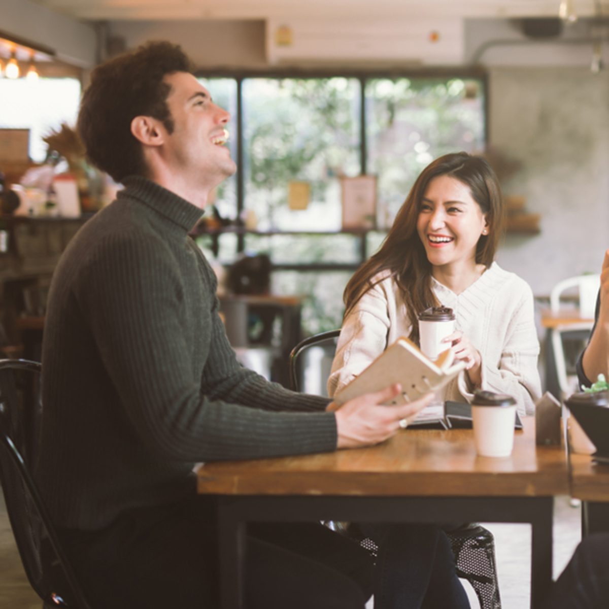 Group of friends chatting and using laptop in cafe at the coffee shop cafe in university talking and laughing together.