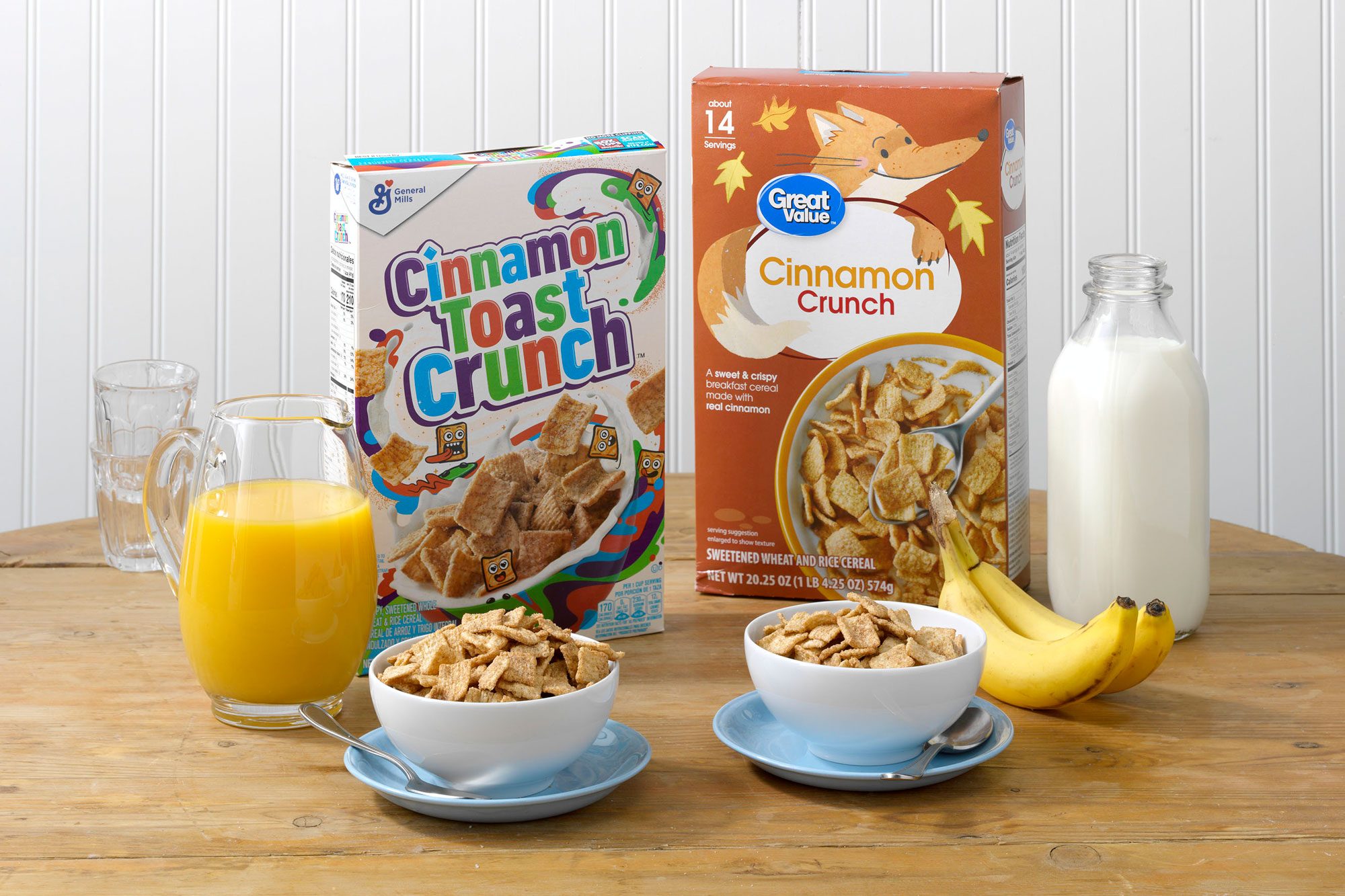 General Mills' Cinnamon Toast Crunch and Walmart's Great Value Cinnamon Crunch on a table with orange juice, bananas, and milk