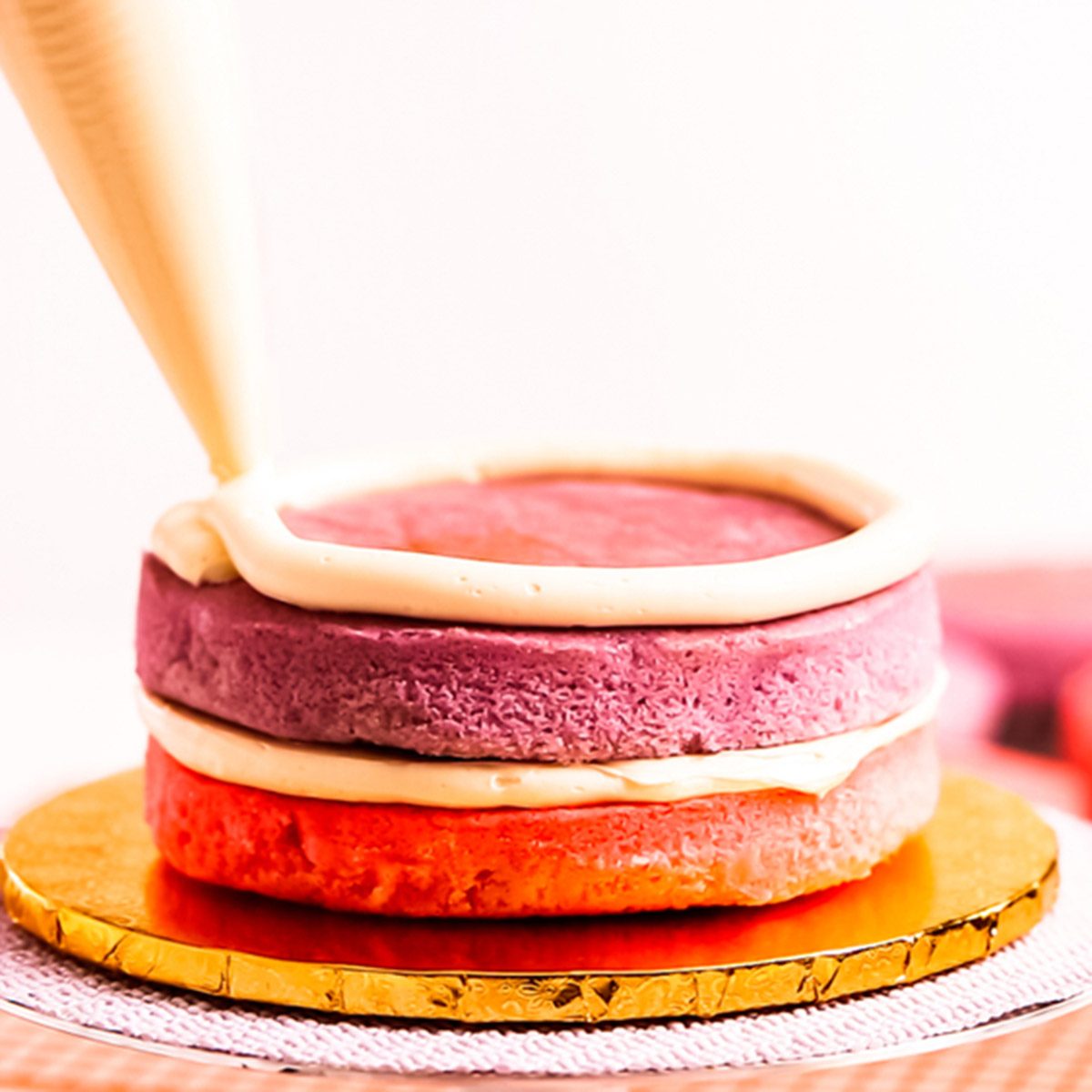 Baker assembling pink and purple cake layer to make unicorn cake for little girl