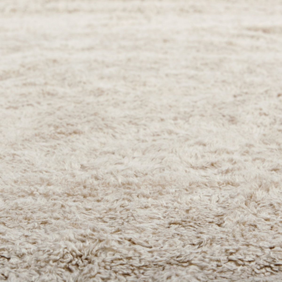 Low close up view of a beige furry carpet texture background