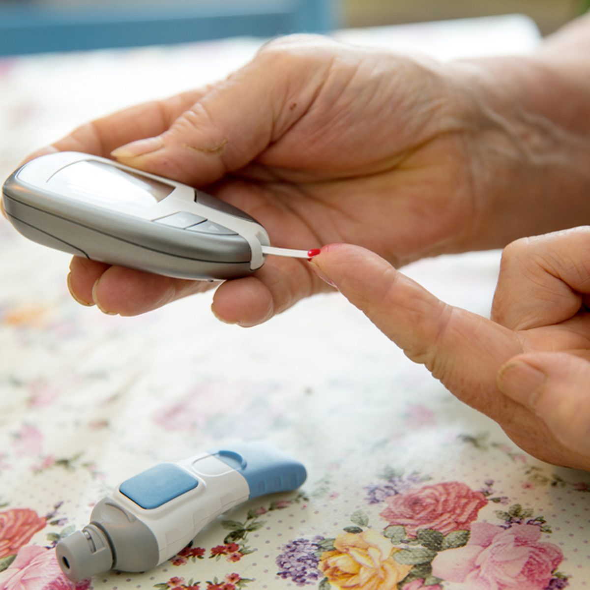 Senior woman is checking her sugar level with glucometer.