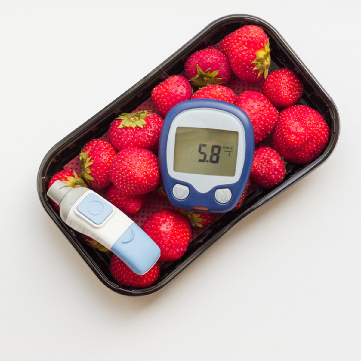 the meter shows normal sugar levels 5,8 mmol/l on background of strawberry.