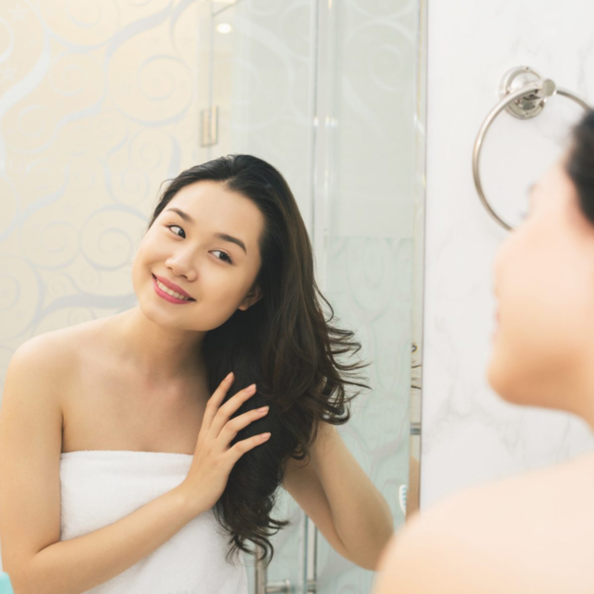 Portrait of attractive woman brushing hair in bathroom