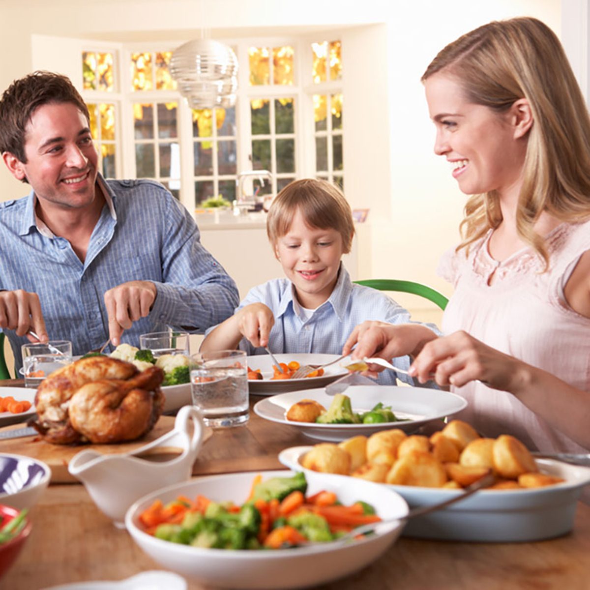 Happy family having roast chicken dinner at table