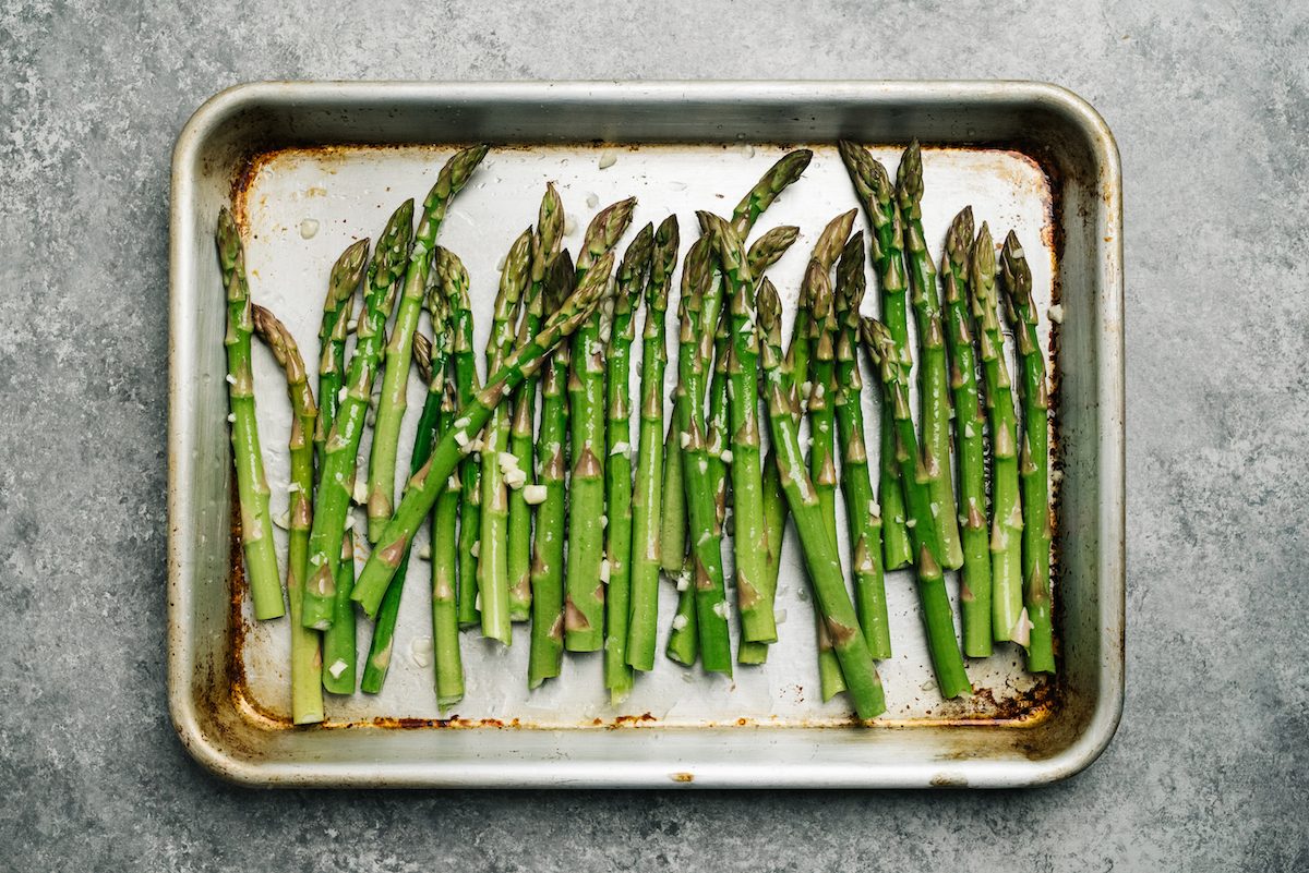 Oiled asparagus on a baking sheet ready to make roasted asparagus.