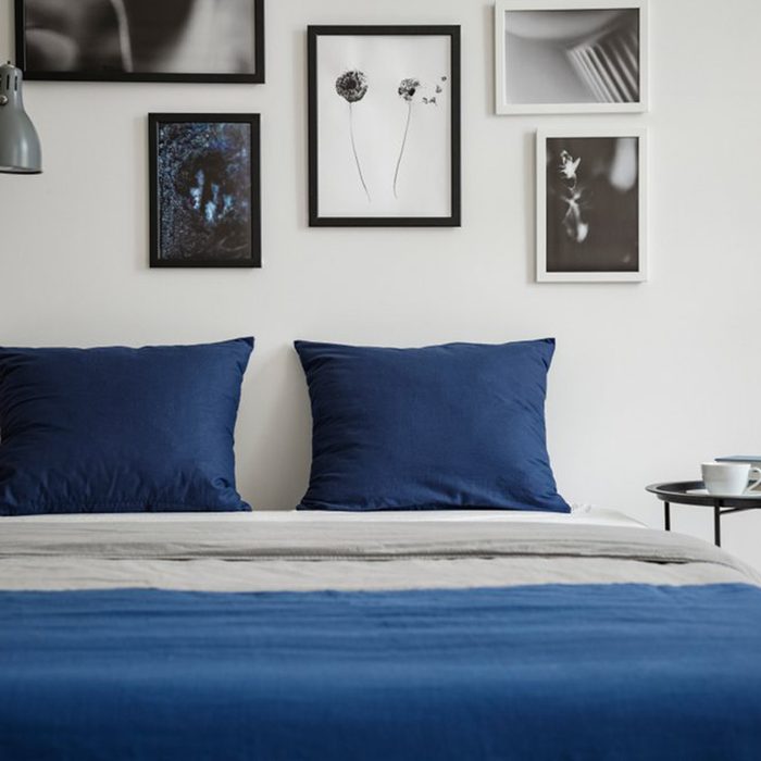 Blue bed with framed photos overhead
