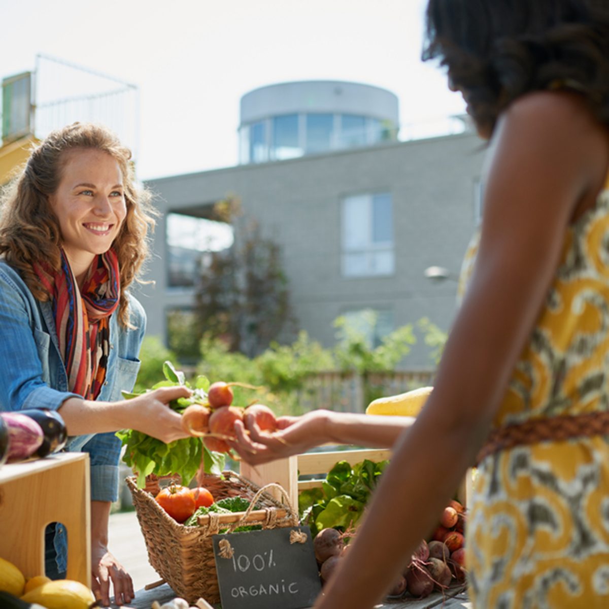 Friendly woman tending an organic vegetable stall at a farmer