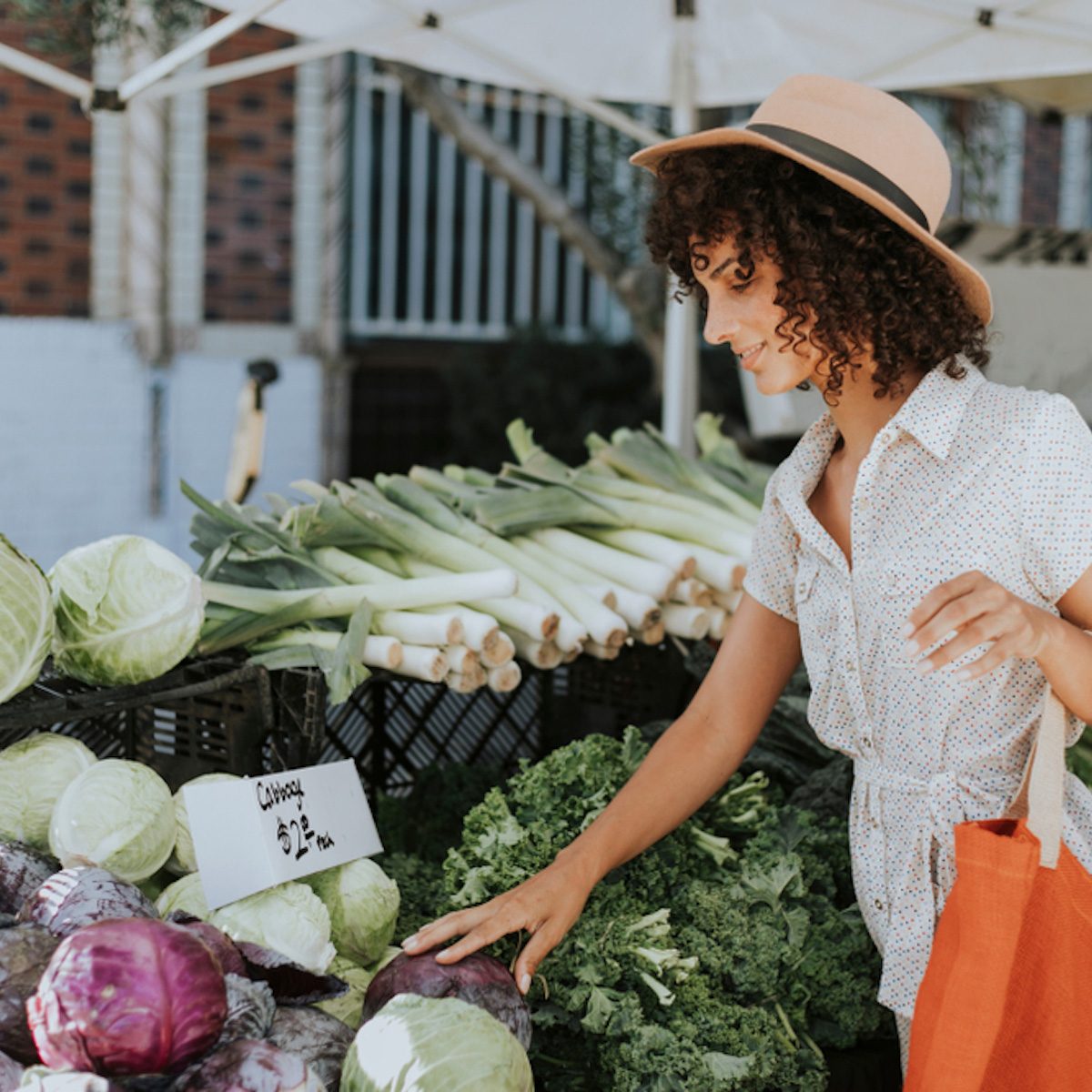 Beautiful woman buying vegetables at a farmers market