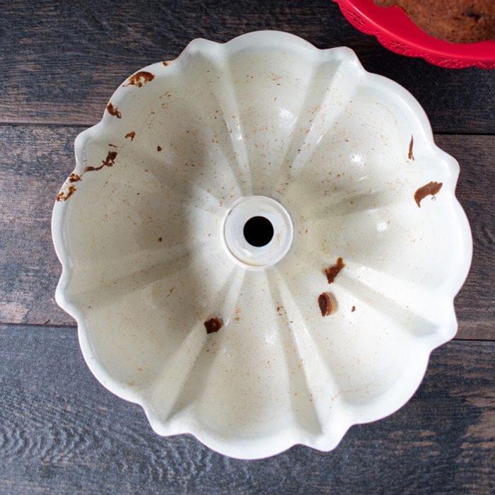 empty red bundt pan with baked carrot cake beside it on farmhouse table top view; Shutterstock ID 1122710399