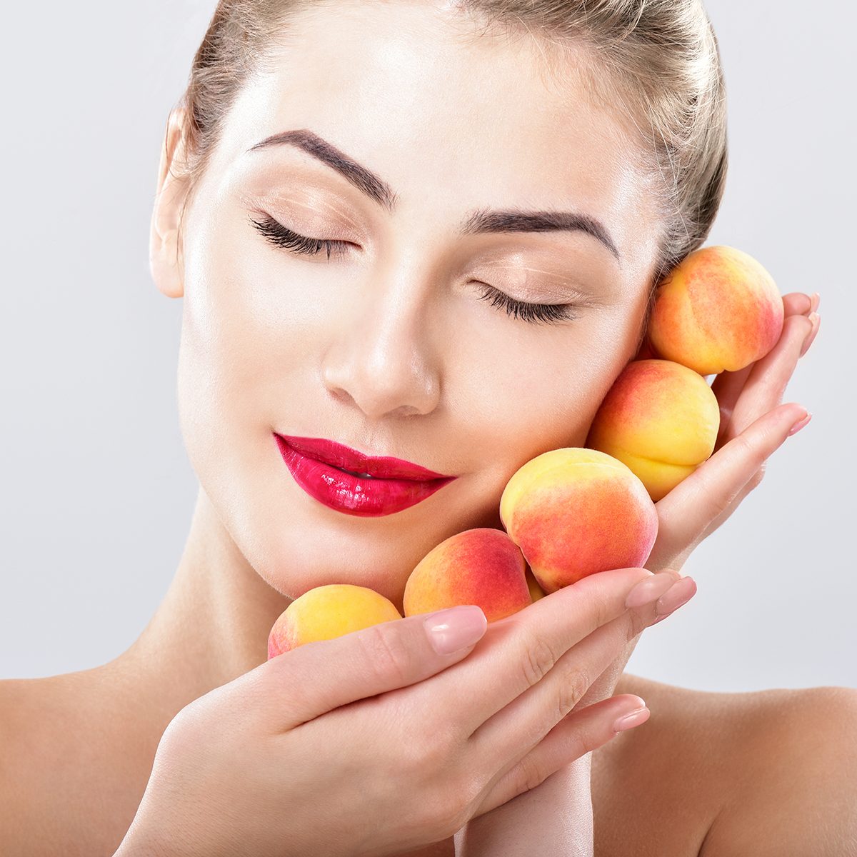 Beautiful woman holding a juicy apricots, peaches. 