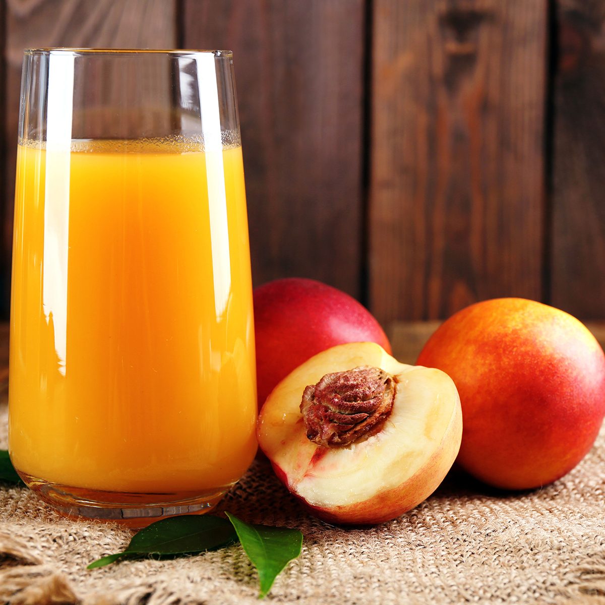Ripe peaches and glass of juice on wooden background