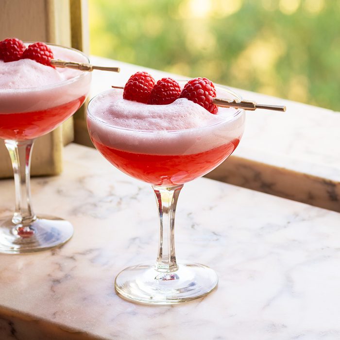 Red Clover Club Cocktails with Layered Egg White Foam and Raspberry Garnish in Marble Windowsill