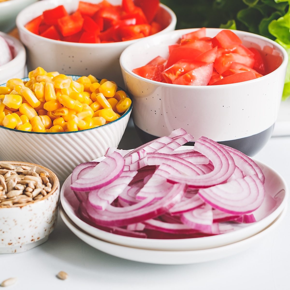 Assortment ingredients for healthy vegetarian salad in different portion bowls on a table.