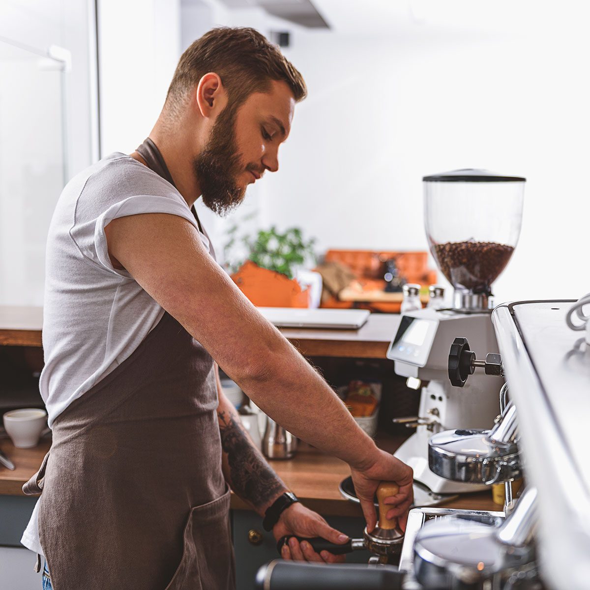 bearded barista tamping ground coffee