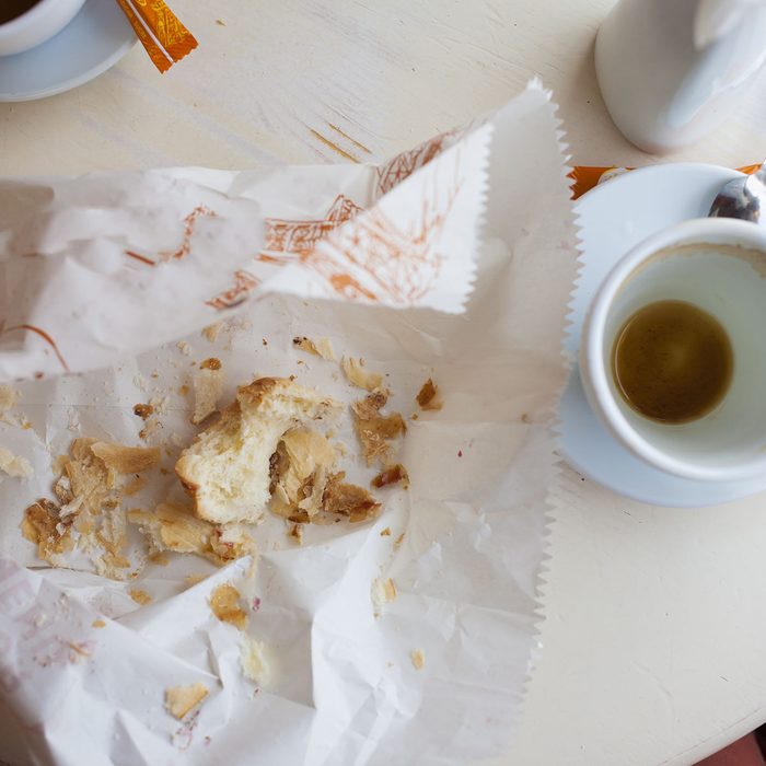Empty coffee Cup and the remains of biscuits are on the table.