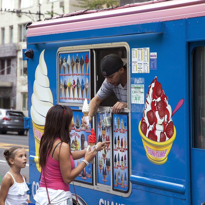 Man sells soft ice cream cone to customers on Columbus Circle.