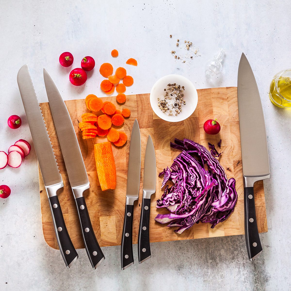 set of new professional kitchen knives on a wooden cutting board and vegetables