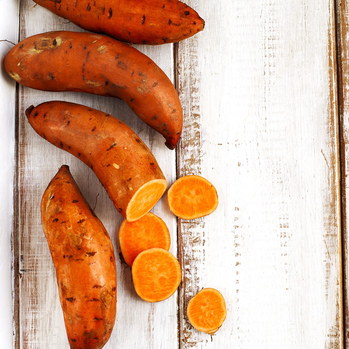 Raw sweet potatoes on wooden background
