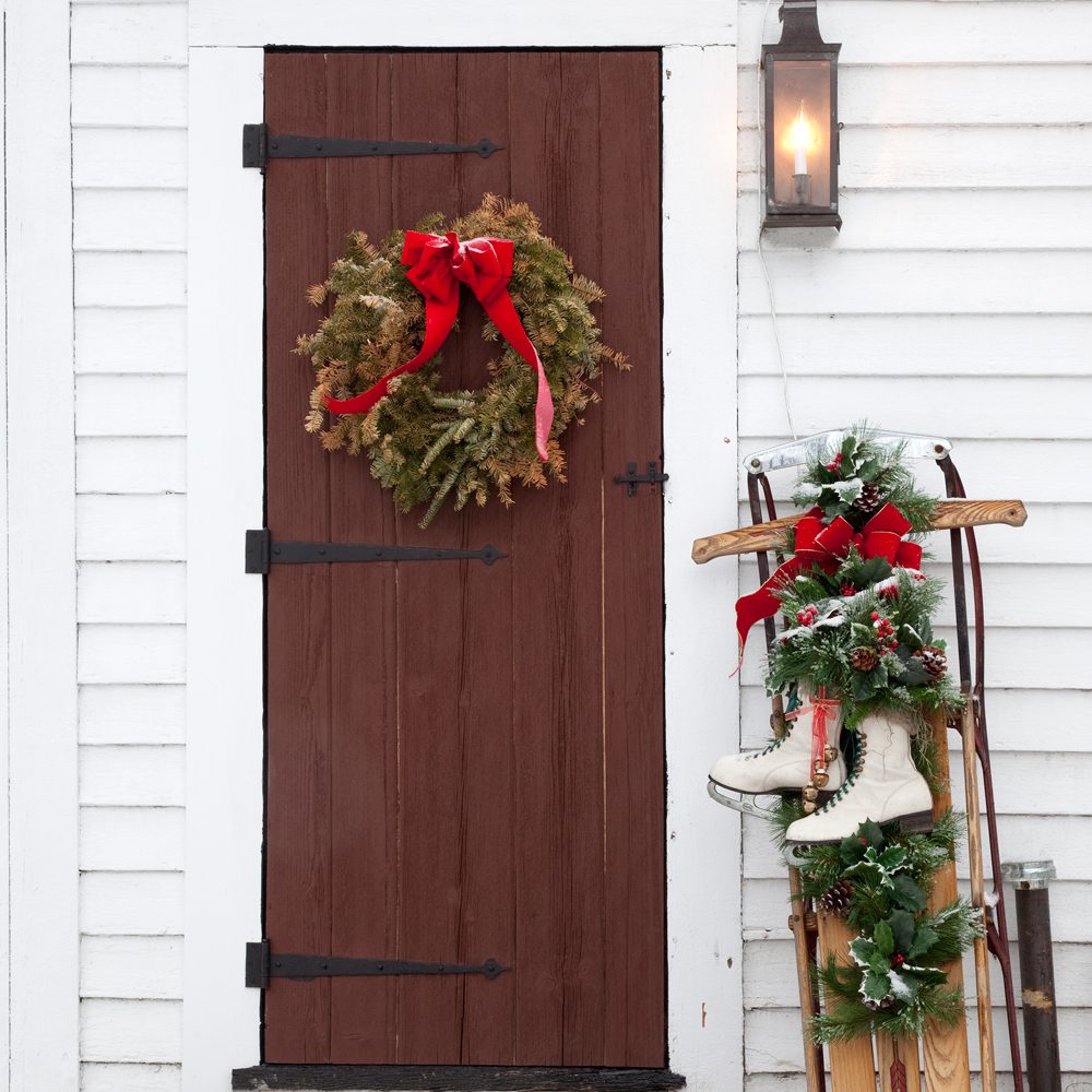 Antique Exterior Wooden Door with Fresh Fallen Snow, an old Toboggan with skates attached leaning against the white exterior of the home