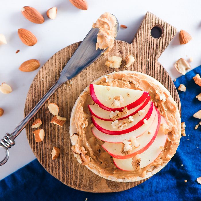 Apple crisp bread toast with apple slices, peanut butter, almonds and walnuts. Healthy breakfast concept in a high key.